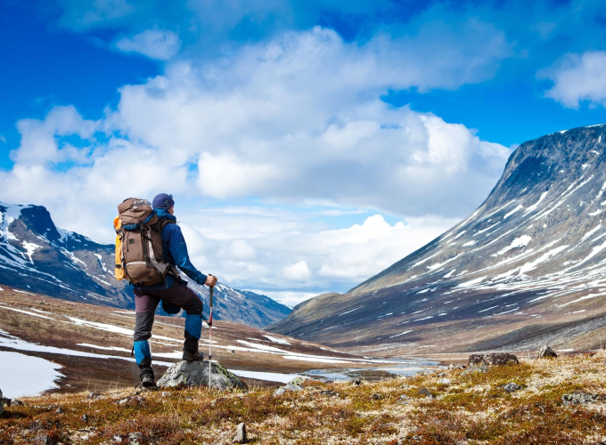 A man with a backpack is standing in the mountains.